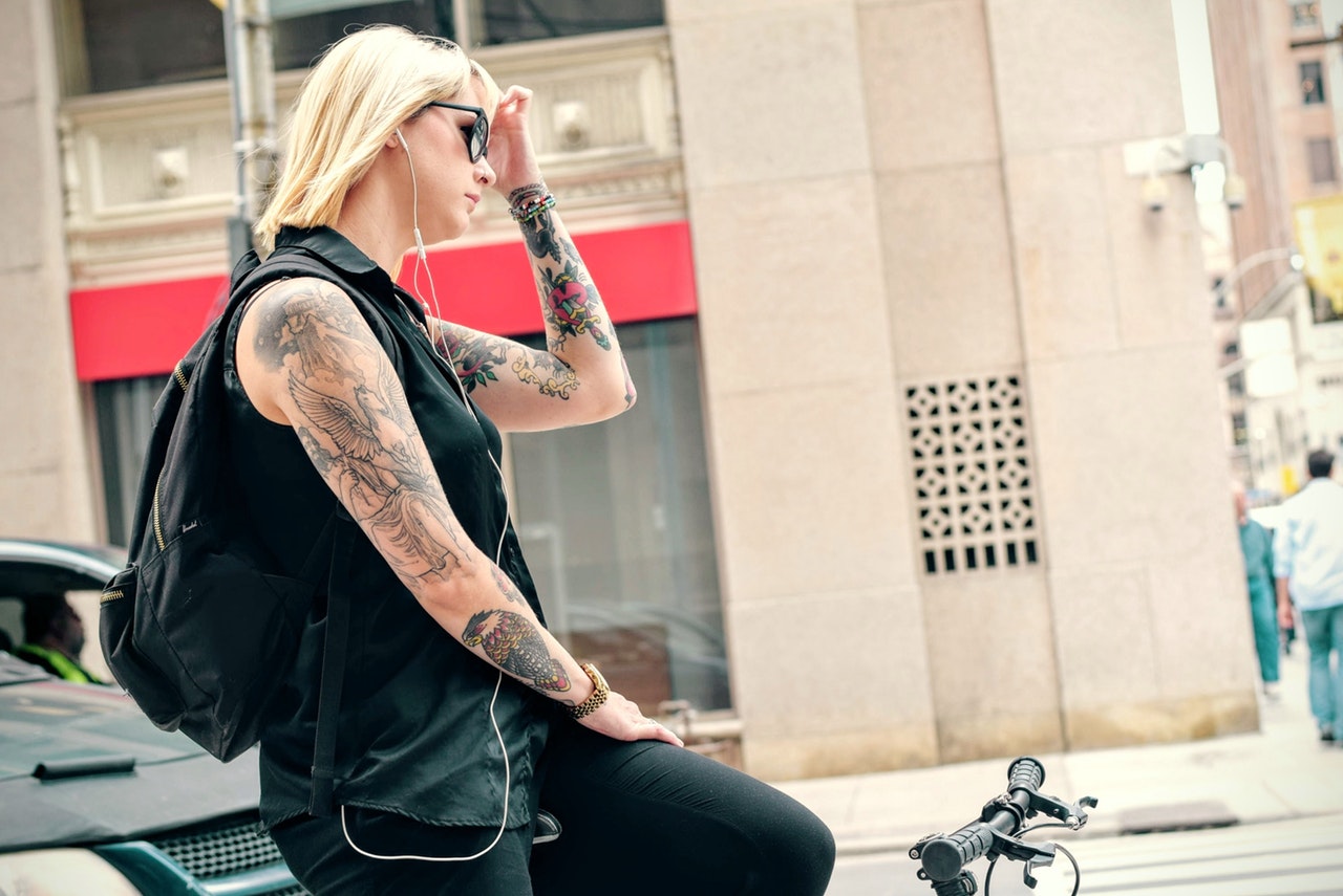A woman on a bike with several large tattoos on her arms